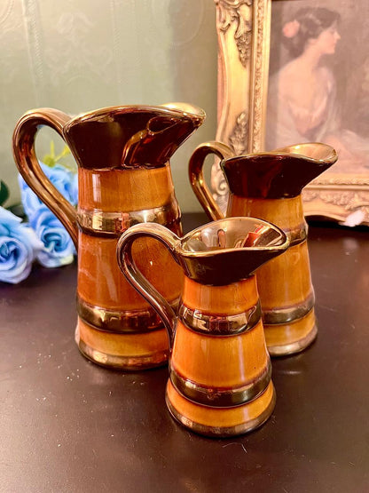 Three amber treacle-glaze jugs grouped together showing graduated sizes