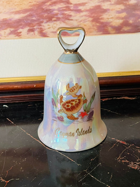 Cayman Islands souvenir, vintage porcelain bell, collectible travel bell, Caribbean souvenir collectibles, sea turtle design bell, iridescent glaze bell, coastal décor vintage, tropical island souvenirs, rare thrift finds, vintage Cayman Islands memorabilia