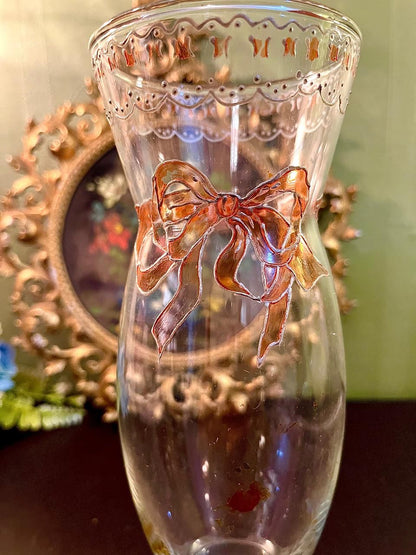 Close-up of hand-painted copper bow motif on glass vase