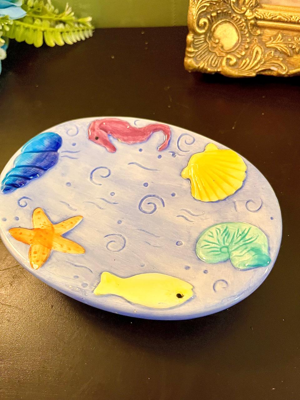 Close-up of starfish, shell and seahorse detail on vintage pastel ceramic plate